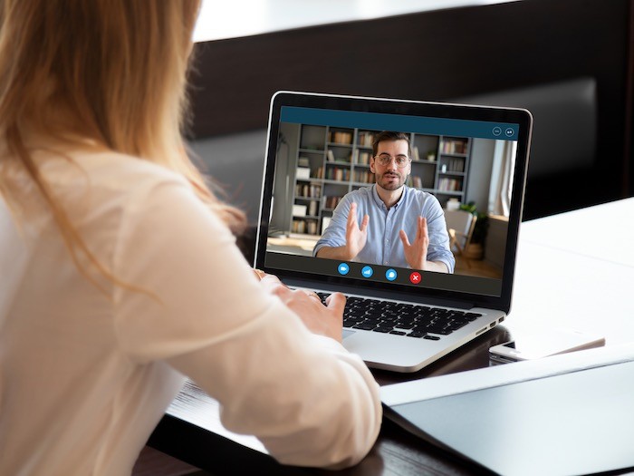 Two people on a video call, with view of one person's background with books.